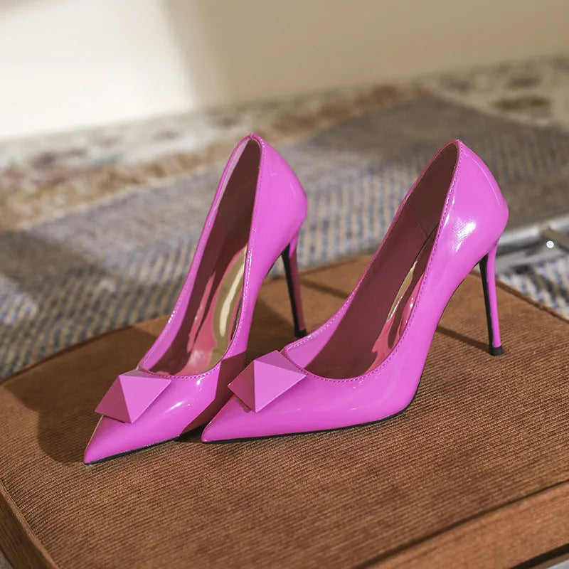 Pink women's patent leather pointed toe stiletto high heels with a buckle strap on a low-top.