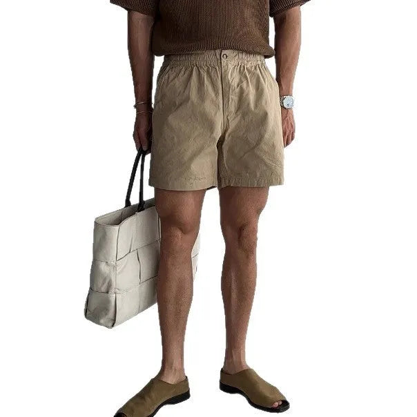 Man wearing black loose-fit cotton sports shorts for summer activity.