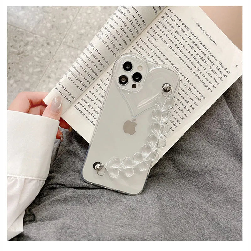 Transparent iPhone case with an attached clear love heart charm bracelet on a TPU shell.