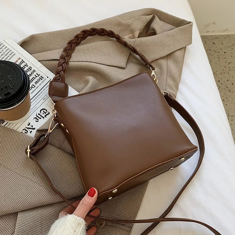 Khaki coloured PU leather one-shoulder crossbody bucket bag with woven detail on the front.
