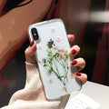 Clear handmade TPU iPhone case with pink dried flowers encased in epoxy resin on the back.