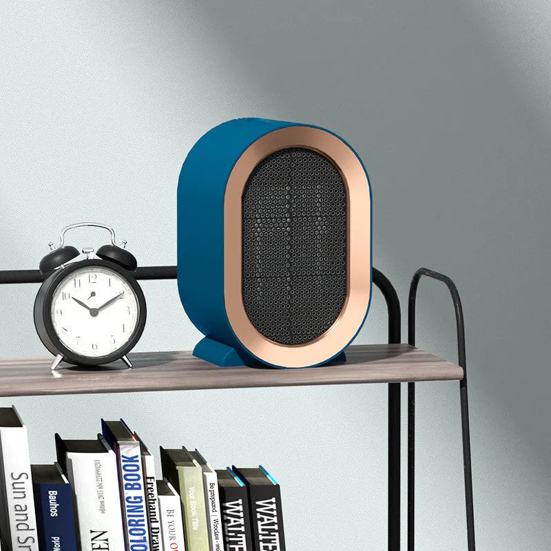 Compact black desktop ceramic fan heater with mechanical controls on a wooden desk.
