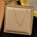 Gold bow necklace on a cross chain, adjustable from 41cm to 50cm length.
