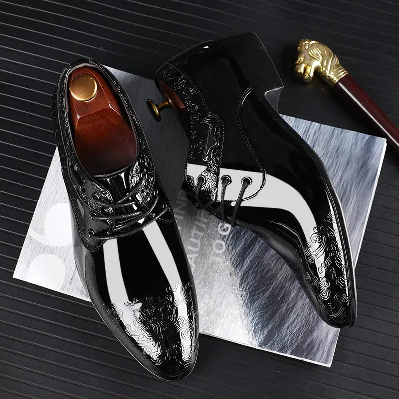 Glossy black men's business formal shoes with patent finish, pointed toe, and carved detail on a neutral background