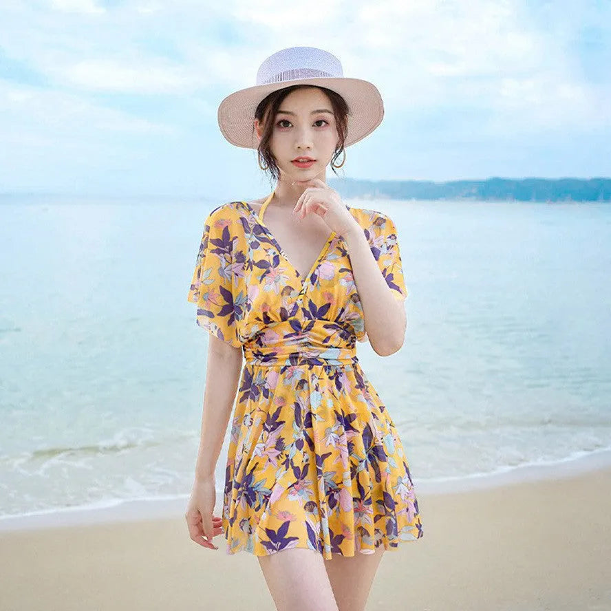 Yellow women's one-piece swimsuit with a floral pattern, shown on a hanger.