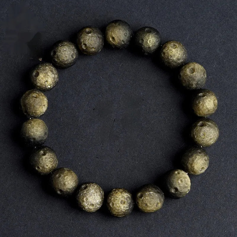 Natural obsidian crater ball bracelet with textured beads in silver stone meteorite colour on a wrist.