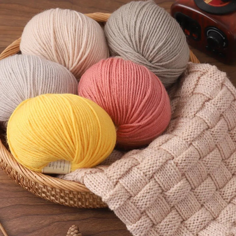 Roll of hand knitting wool yarn for baby clothes in assorted colours including green, beige, and red.