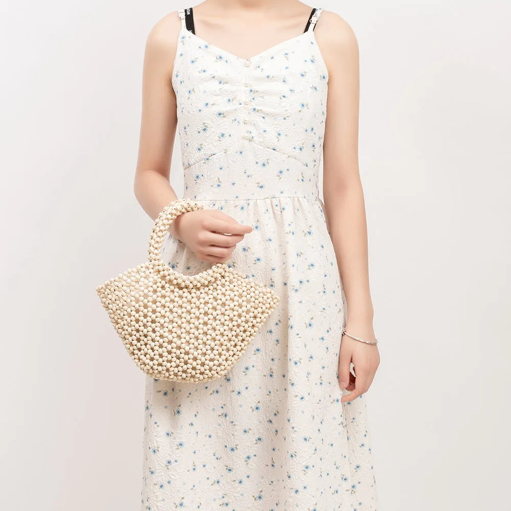 Hand-woven dumpling-shaped beach bag with wooden beads in milky white.