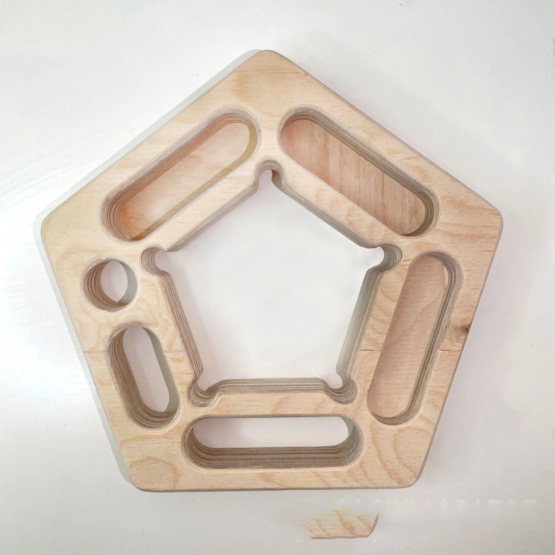 Birch wooden pentagonal-round climbing finger force training plate on a neutral background.