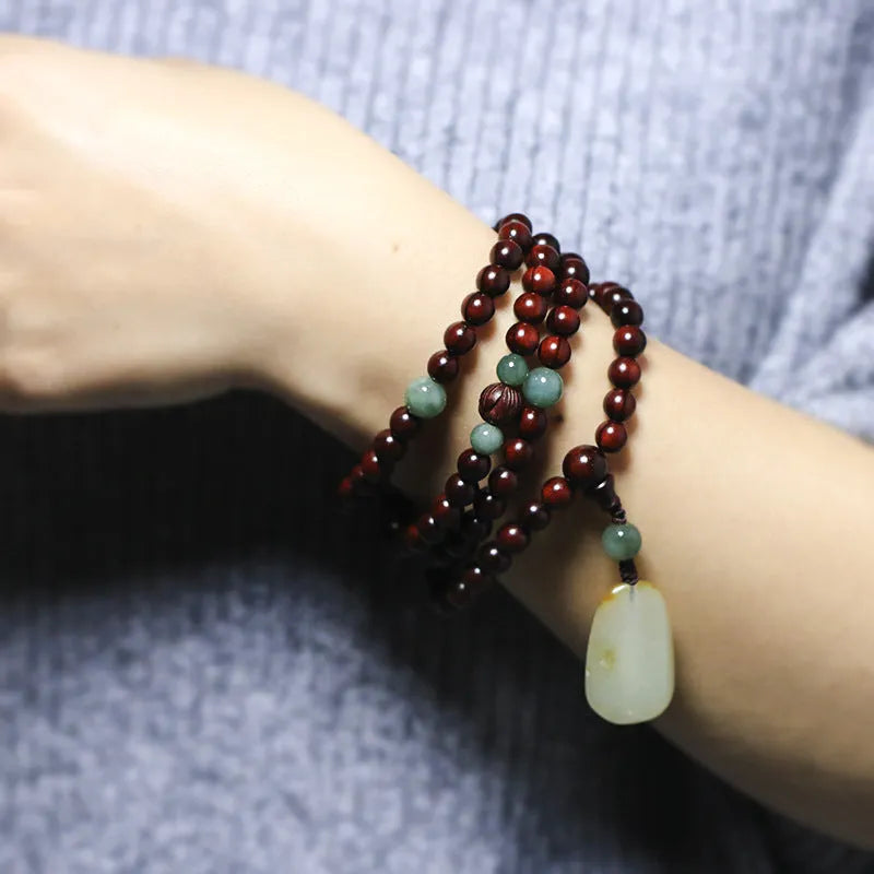 Rosewood beaded bracelet with carved wood elements and green Hotian jade pendant on wrist