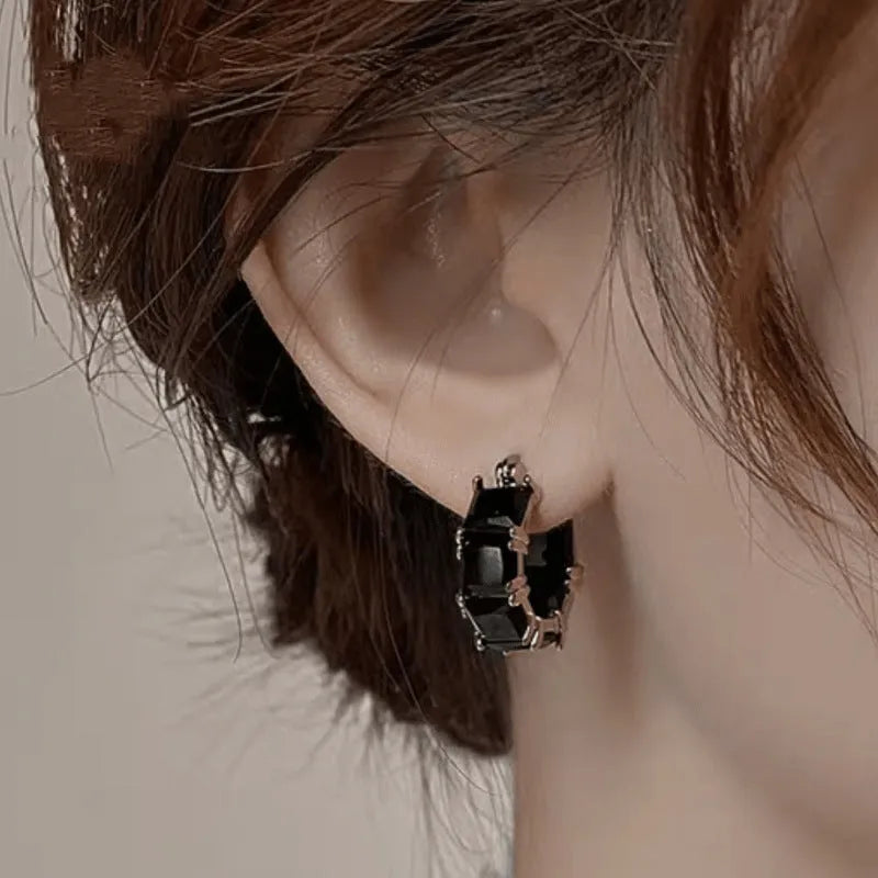 Geometric gold U-shaped hoop earrings with a round black zircon stone, shown from a side view.