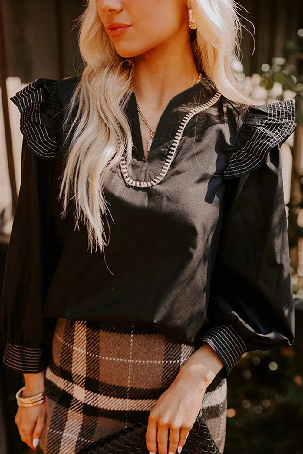 Black women's long sleeve blouse with V-neck, ruffle sleeves, and contrast stitching.