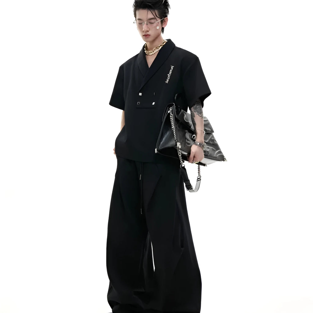Men's dark grey cotton sports suit with V-neck short sleeve top, padded shoulders, metal embellishments, and matching shorts.
