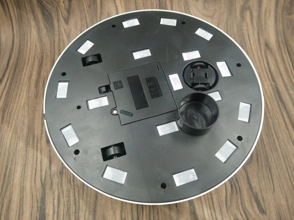 Black automatic sweeping robot cleaner on a wooden floor.