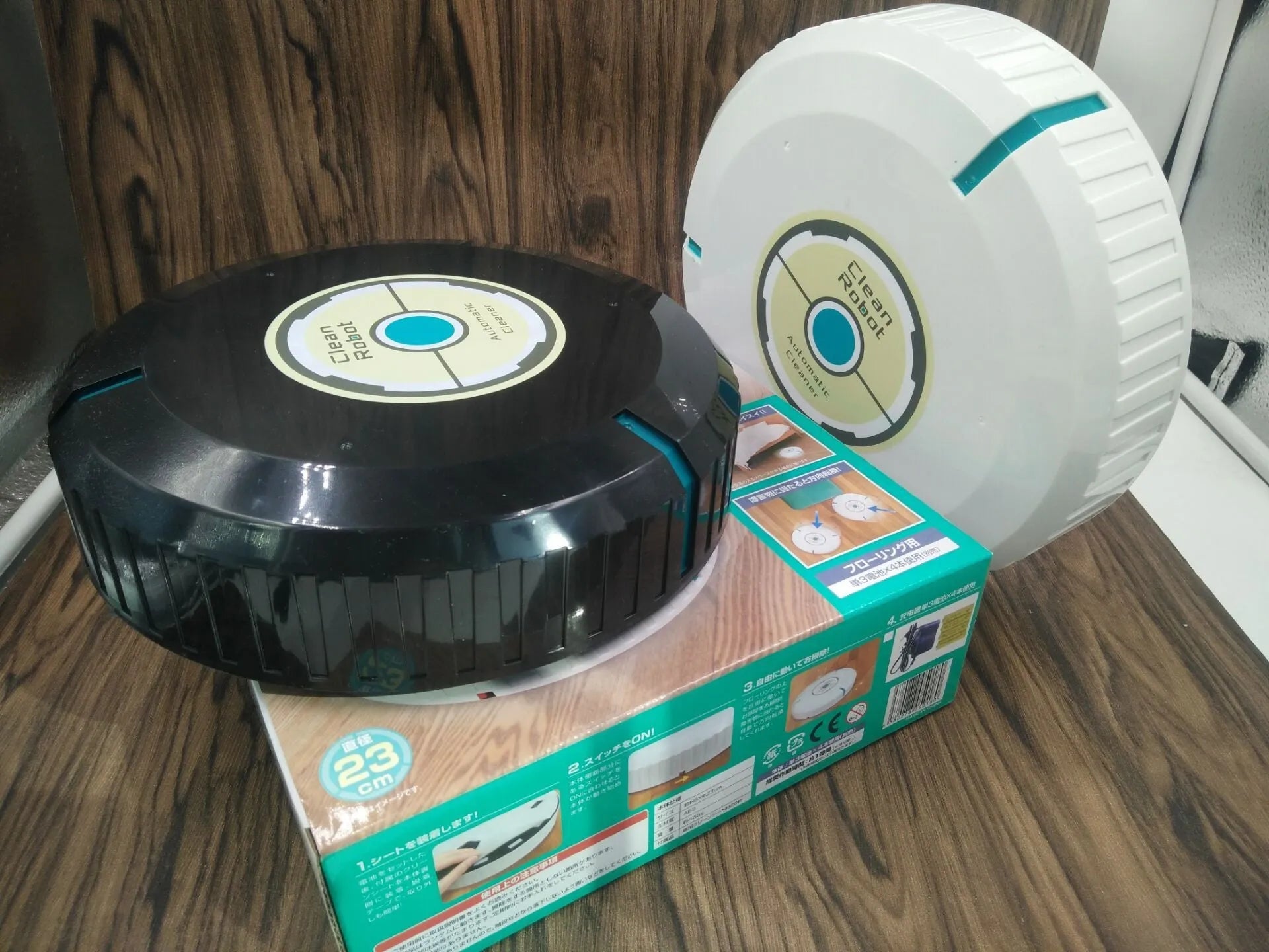 Black automatic sweeping robot cleaner on a wooden floor.
