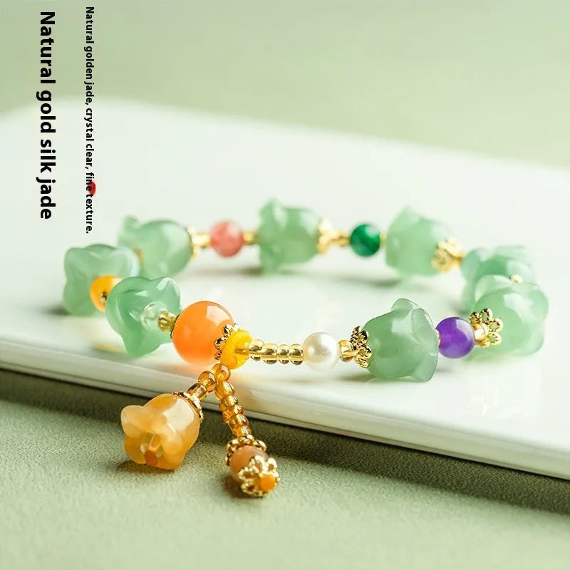 Close-up of a carved orchid bead jade bracelet in aventurine orchid colour on a wrist.