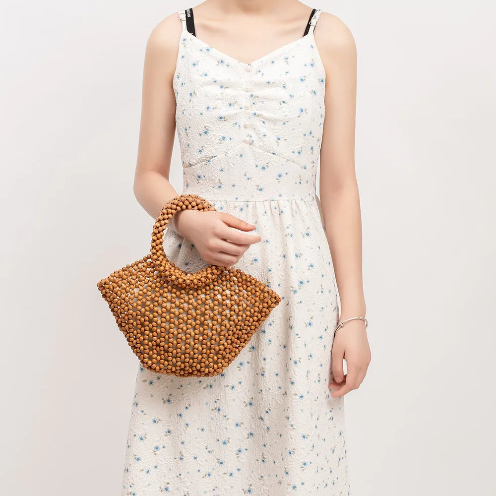Hand-woven dumpling-shaped beach bag with wooden beads in milky white.