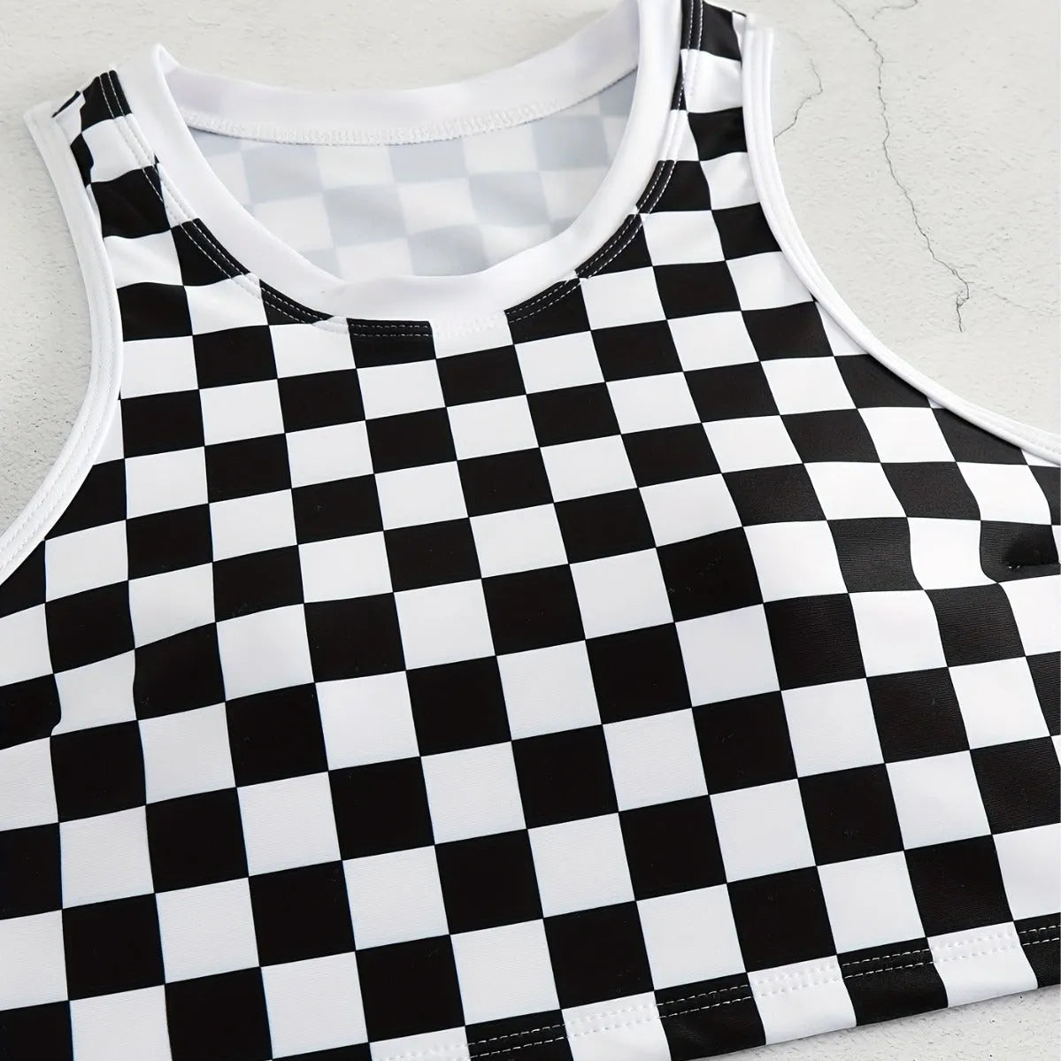 Women's backless racing one-piece swimsuit with suspenders in a black and white chessboard pattern.