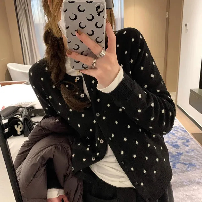 Grey dot patterned women's knitted cardigan with crochet flower details on a hanger.
