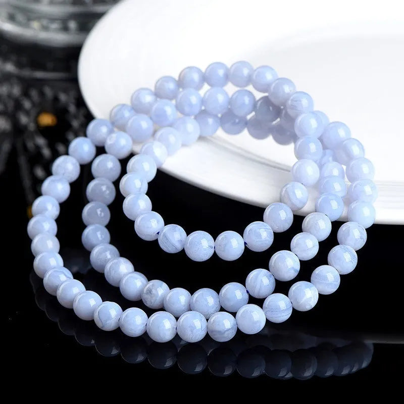 A blue agate bracelet with a natural striped pattern and scattered beads on a wrist.