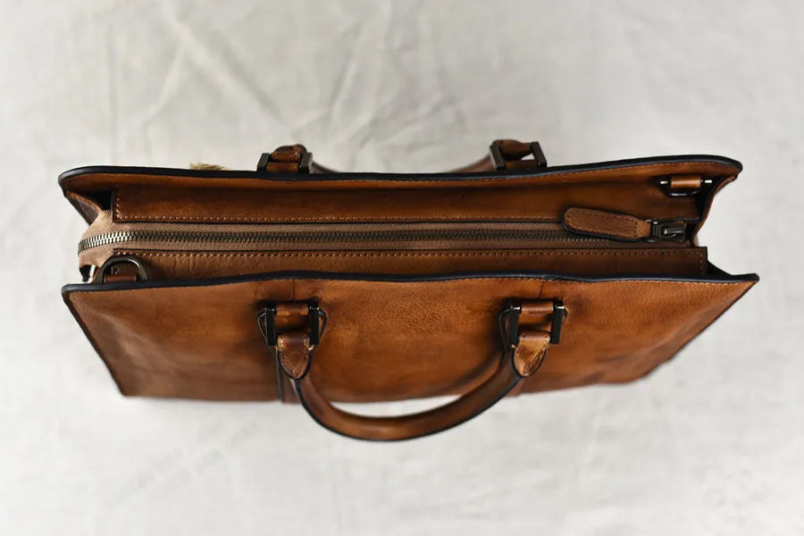 Men's brown leather horizontal business handbag with zippered closure on wooden surface