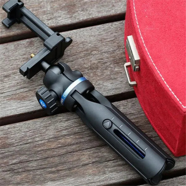 Black desktop tripod holding an iPhone, made from aluminium alloy and plastic, on a wooden table.
