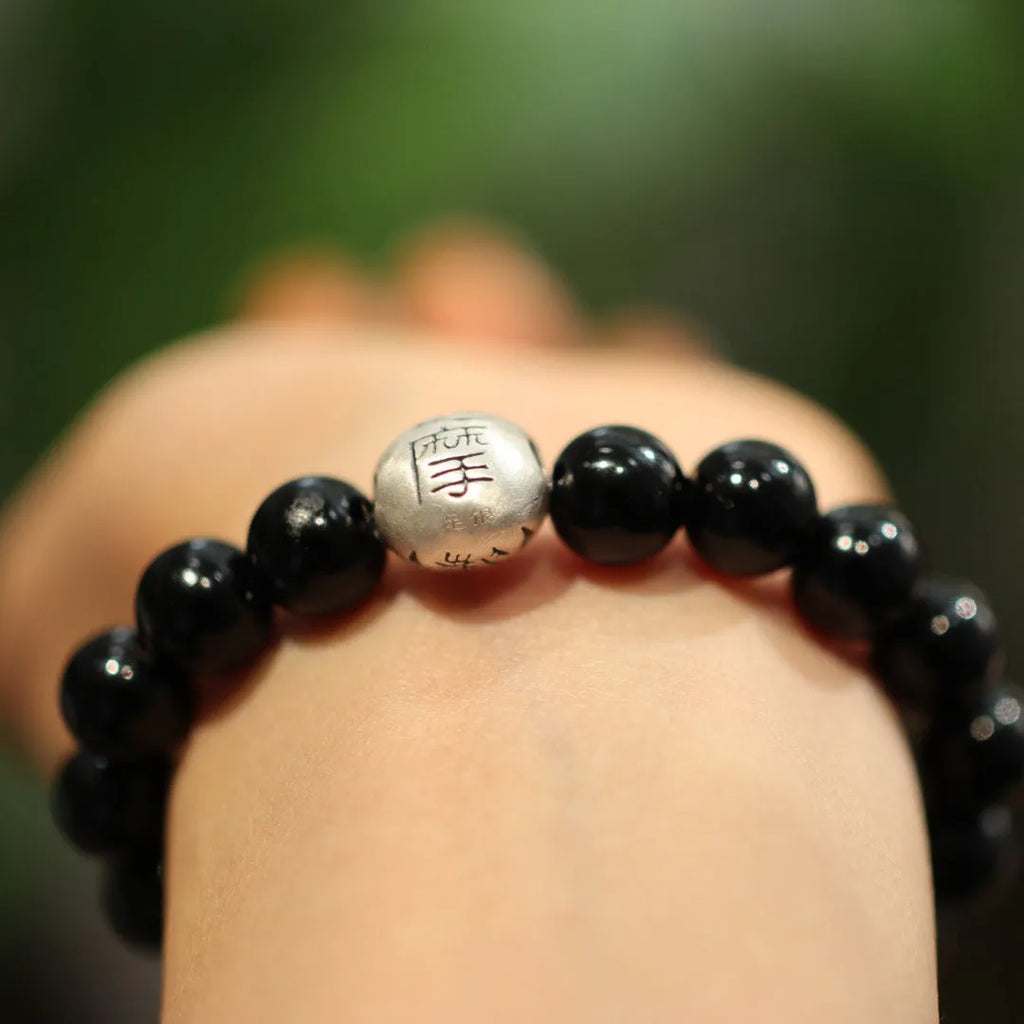 Close-up of a women's bracelet with a large 10mm black agate bead and sterling silver clasp in a Chinese style design.