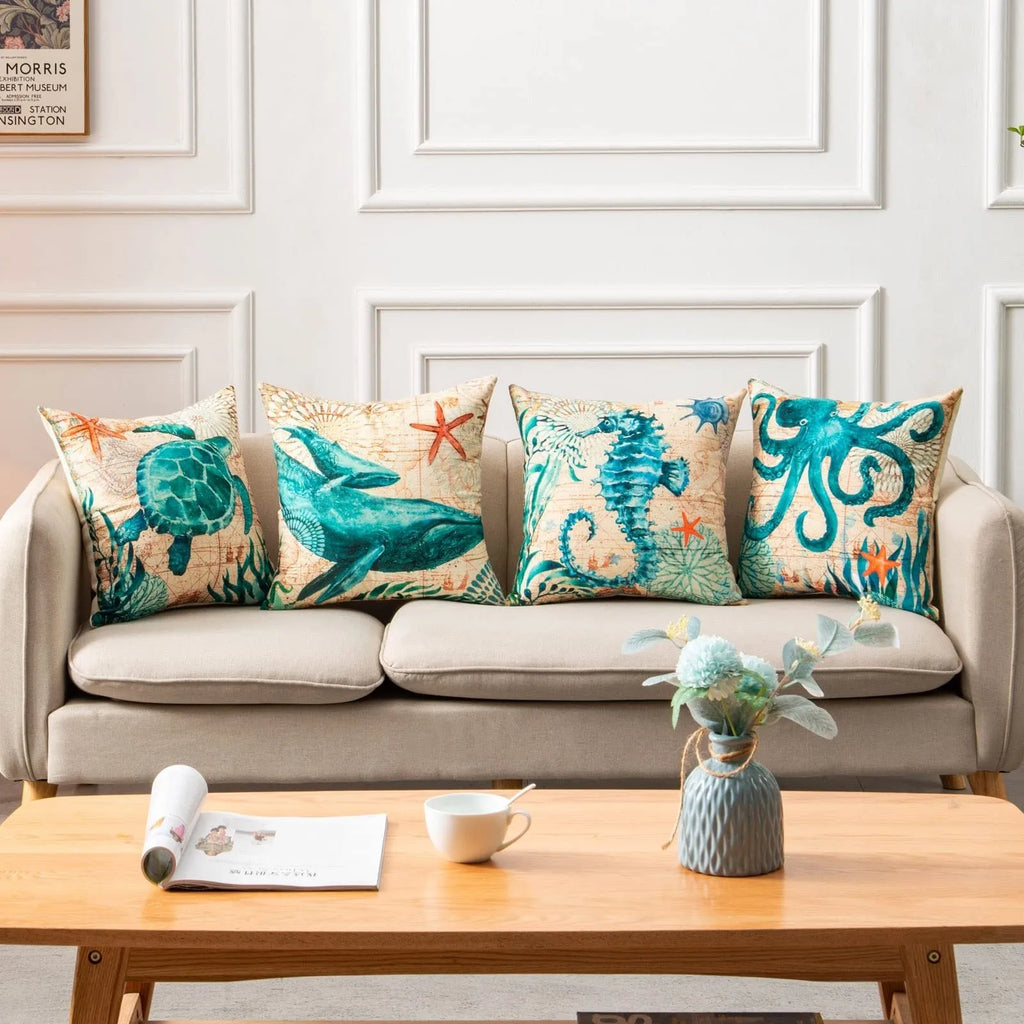 Square linen cushion cover with a detailed blue and green sea turtle print, shown on a grey sofa.