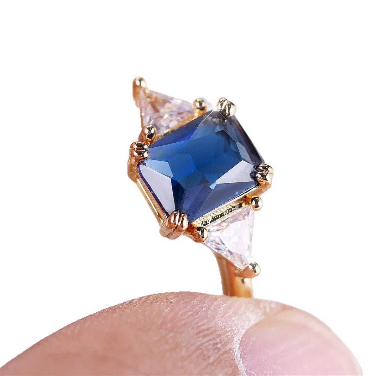 Women's rectangular copper ring in gold sapphire blue on a neutral background, showing its geometric band shape.