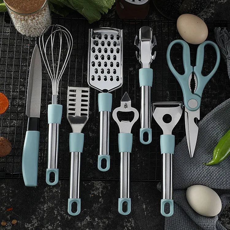 Stainless steel kitchen gadget set with peeler and whisk on grey tray