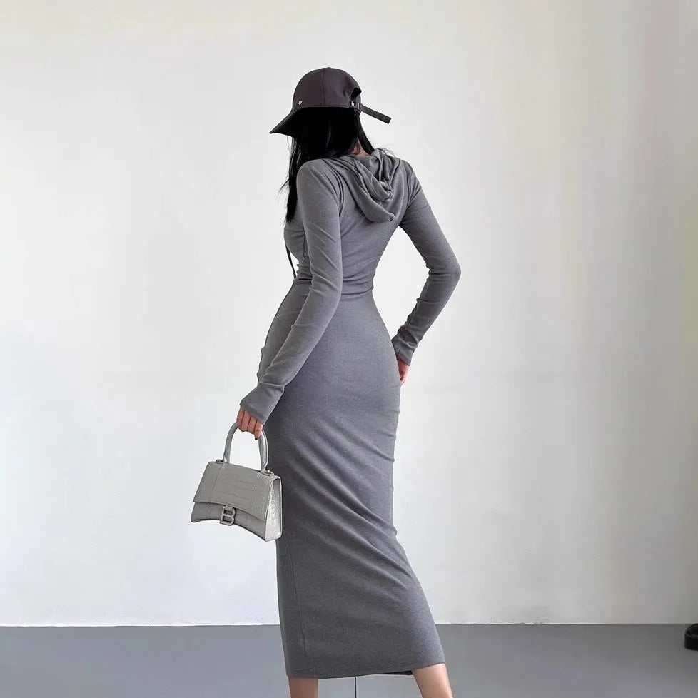 A woman wearing a light grey, long-sleeve polyester sheath dress with an over-the-knee length and high waist.