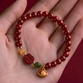 Emperor Sandstone Happy Eyebrow Bracelet with cinnabar accents and fu character charm on wrist.