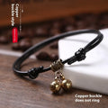 Black nylon rope dog collar with a shiny brass bell on a wooden surface.