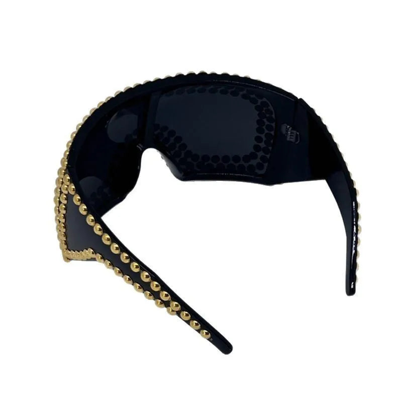 Men's square punk sunglasses with large rim and silver rivets on a dark background.