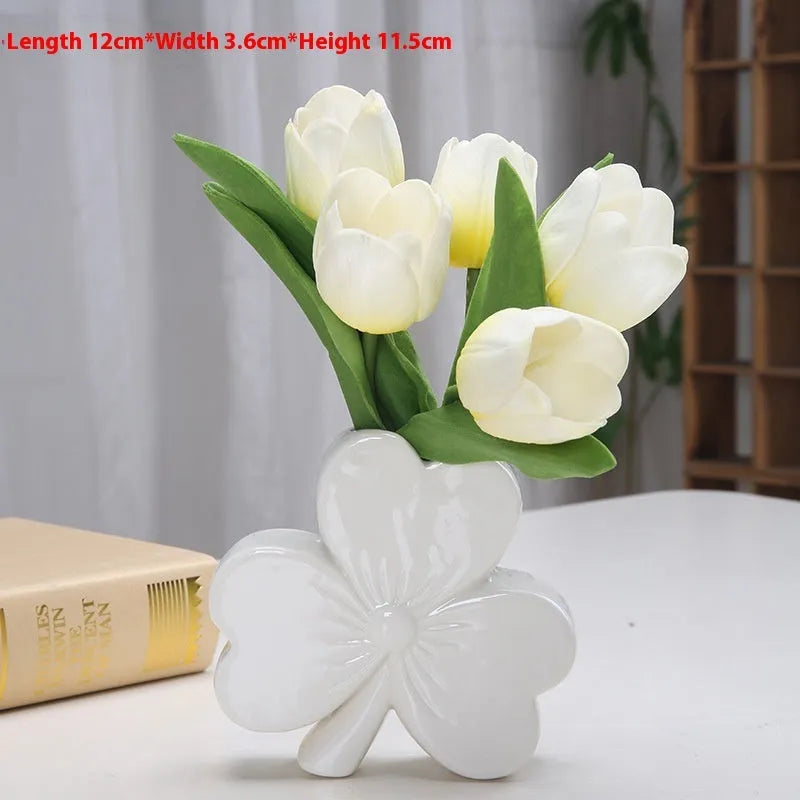 White porcelain clover-shaped ceramic vase in European style, on a desktop.