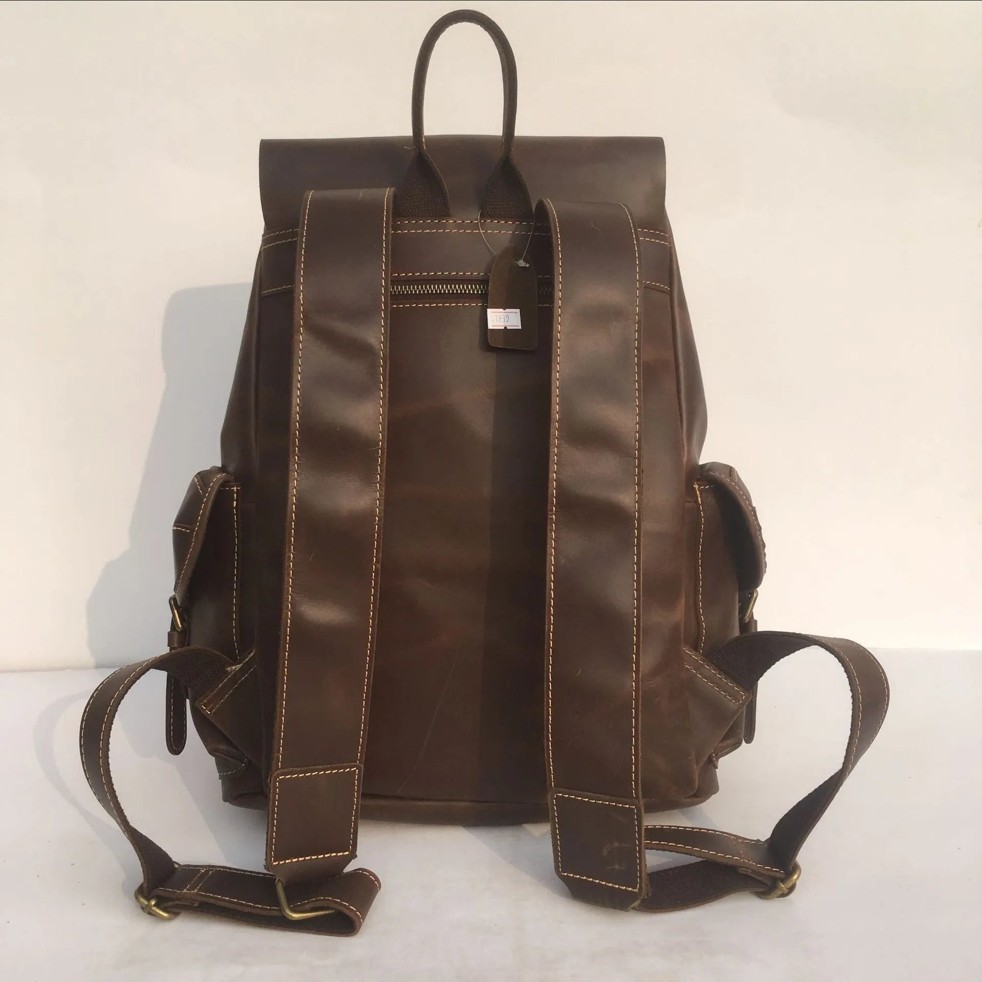 Brown men's leather backpack with an air-pillow belt system on the back.