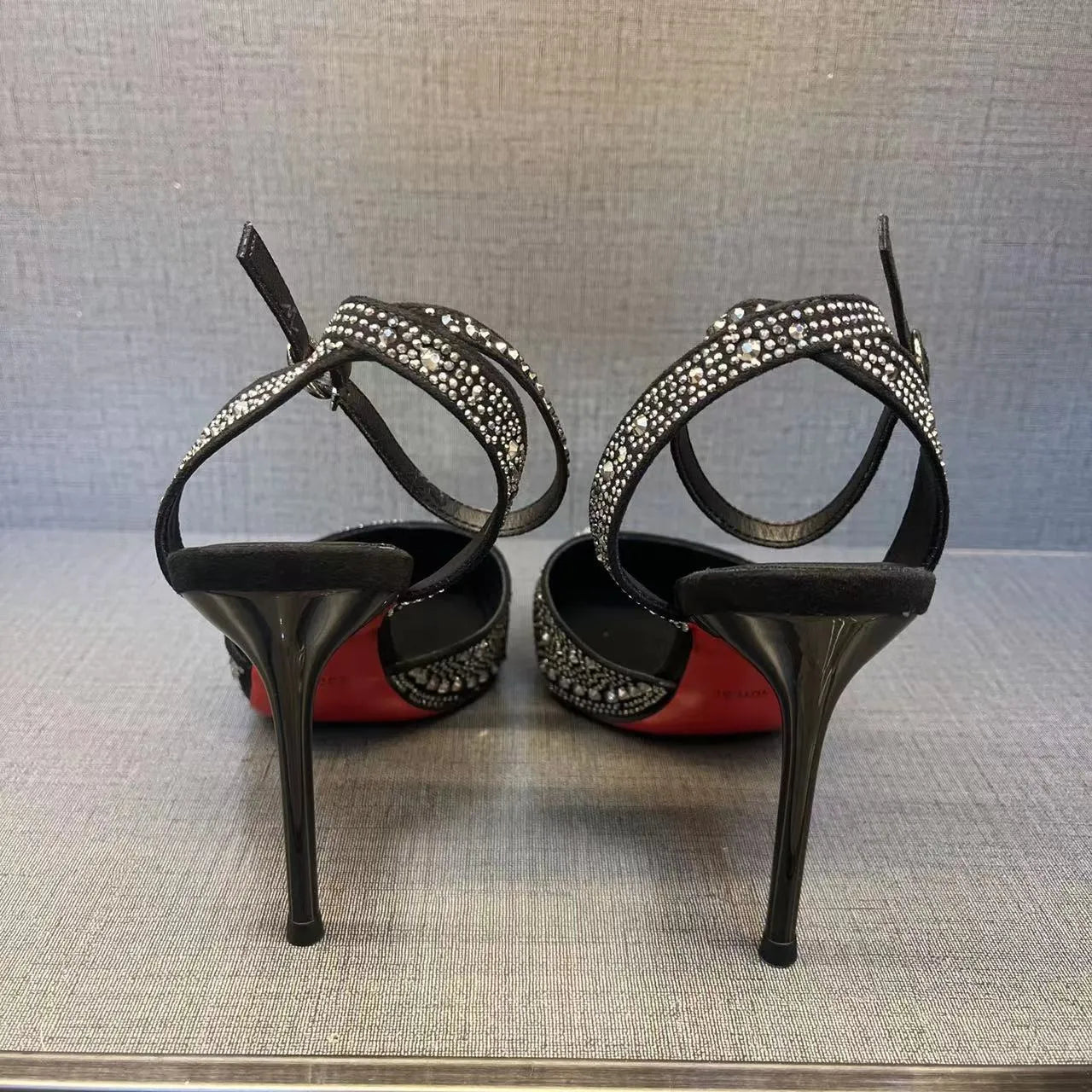 Women's black and silver hollow high heels with a red sole and pointed stiletto toe.