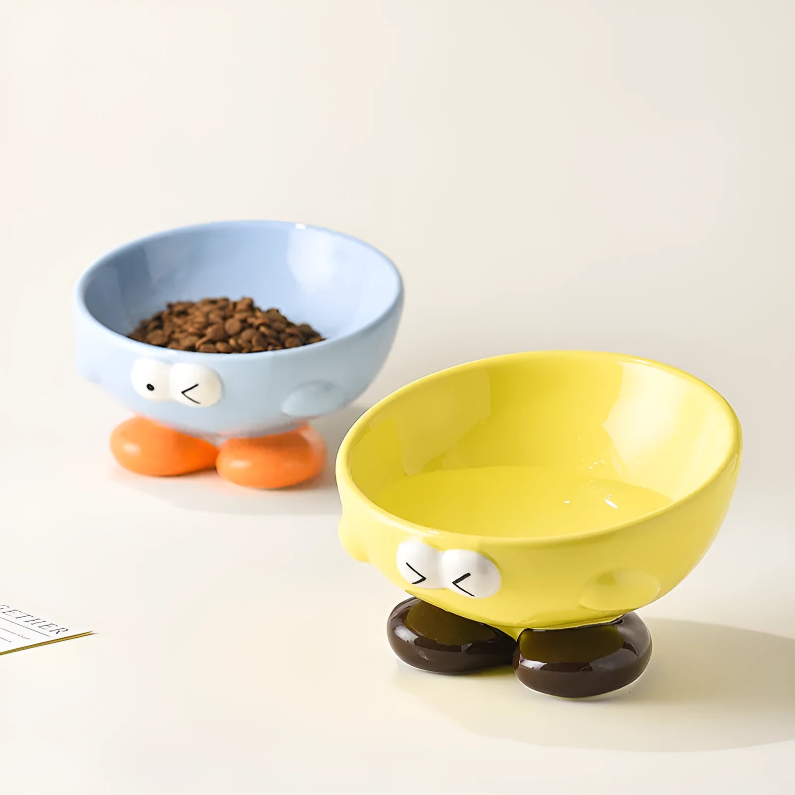 Blue ceramic oblique pet bowl with tall sides and a cute expression print for cervical spine support.
