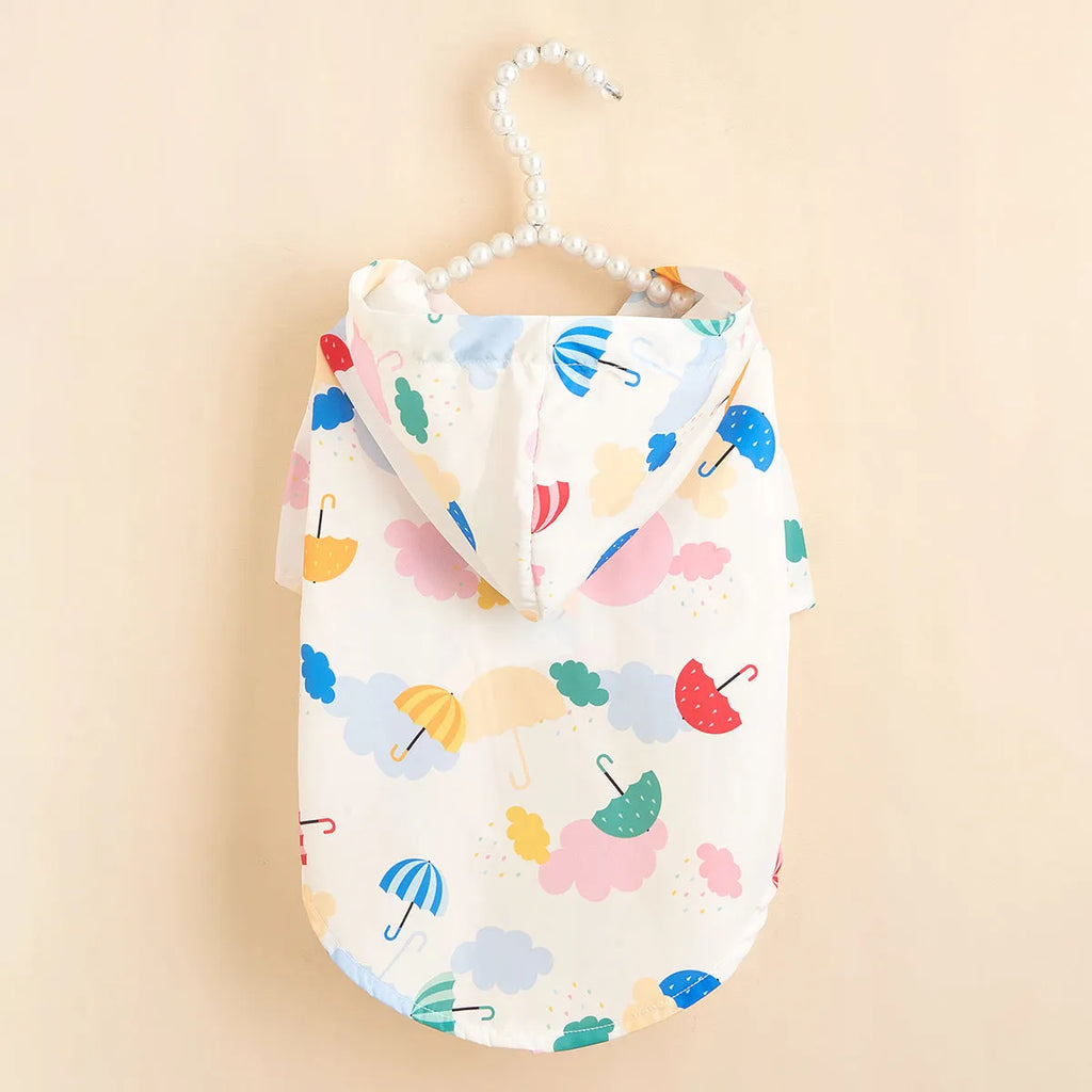Cartoon umbrella pattern colourful dog raincoat on a small dog, showing strap and buckle closure.
