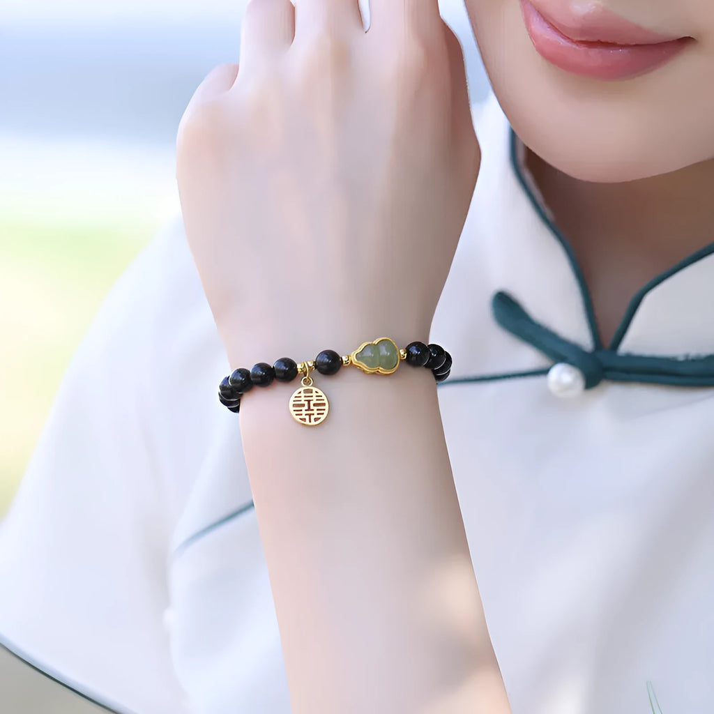 Black obsidian bracelet with carved Hetian jade gourd charm showing geometric patterns