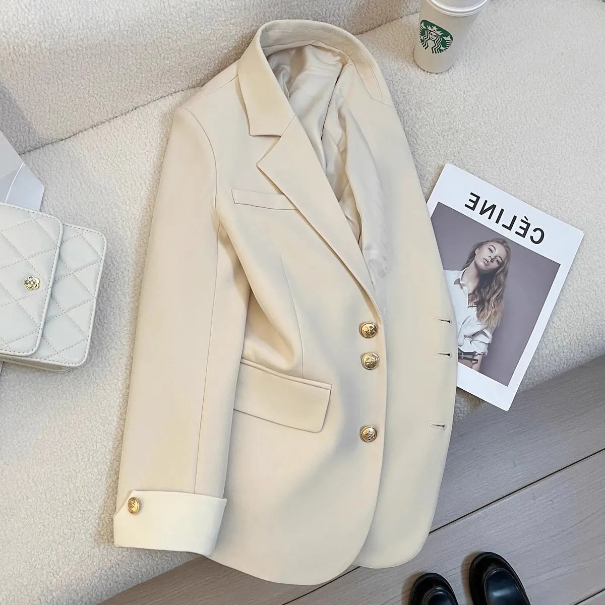 Milky white loose-fit mid-length women's coat with long sleeves and pockets on a hanger.