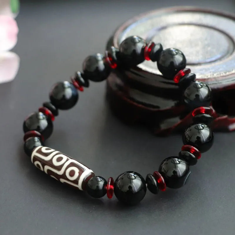 Black agate dzi bead bracelet with hand-woven geometry beads on a wrist.