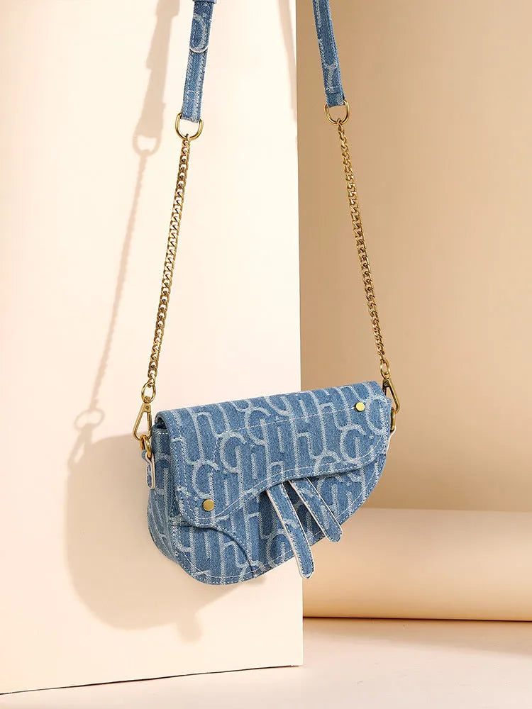 Women's vintage denim saddle bag in blue with cross-body strap and zip pocket interior