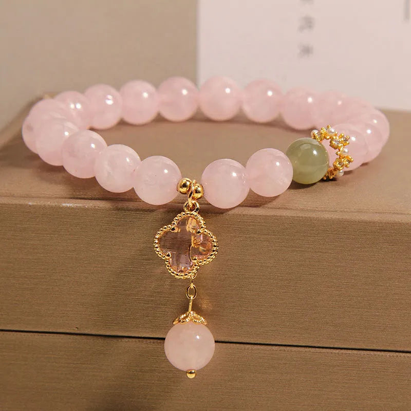 Pink crystal bracelet with four-leaf clover pendant and rhinestone details on women's wrist