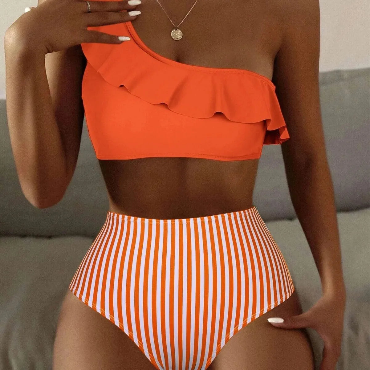 Women's striped and solid colour two-piece bikini swimsuit on a neutral background