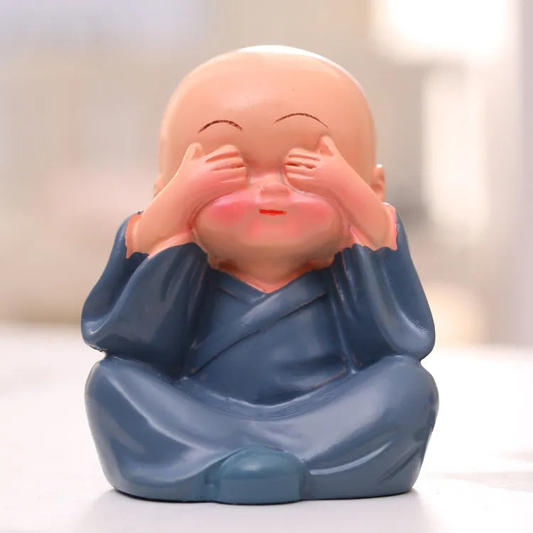 Set of 4 miniature resin Buddha monk statues in blue, brown, gray, and orange, 4.7 cm tall, on a shelf