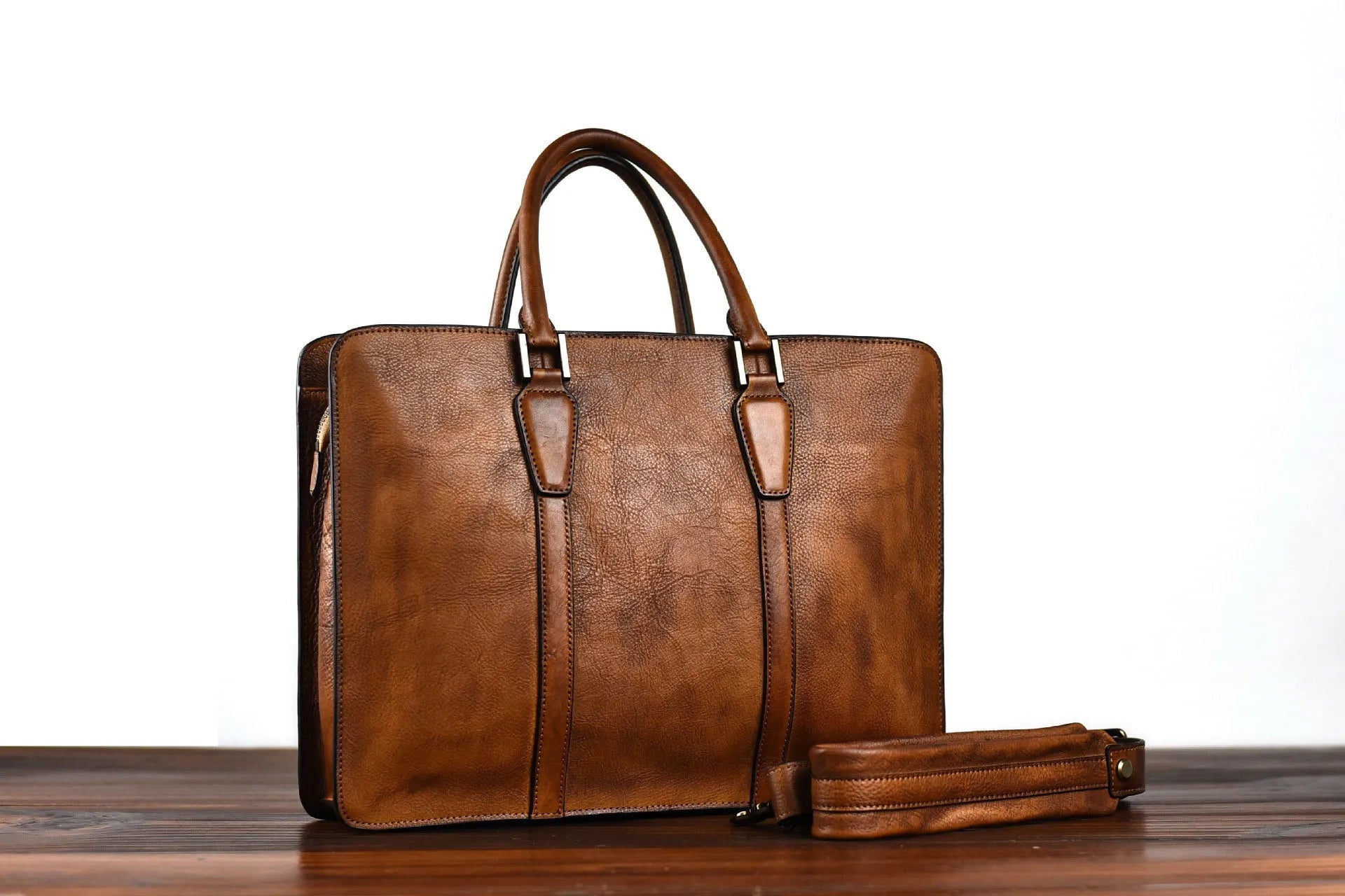 Men's brown leather horizontal business handbag with zippered closure on wooden surface