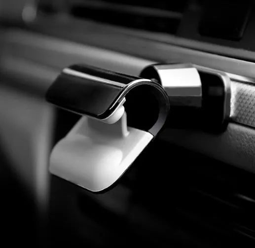 Black universal car phone holder with 360-degree rotating head on a car dashboard.