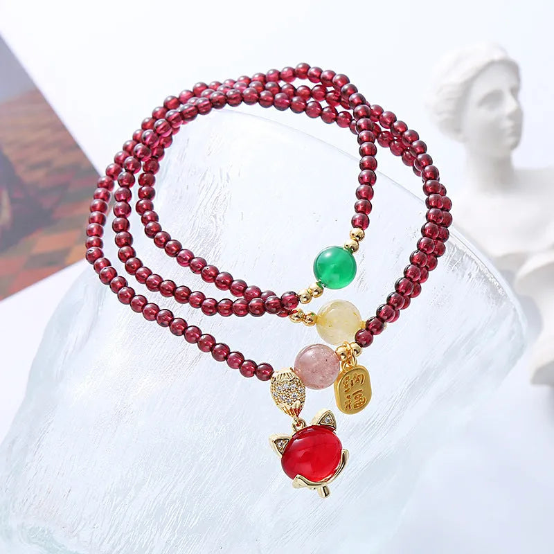 Purplish red garnet fox charm on an adjustable rope bracelet for women.