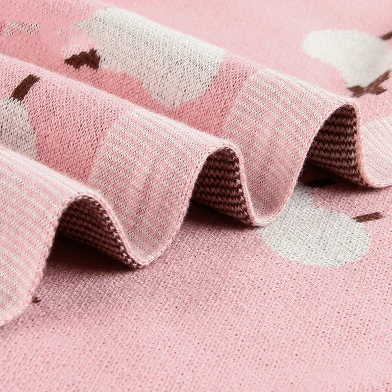 A pink baby sheepskin blanket measuring 100 by 80 cm on a pram.